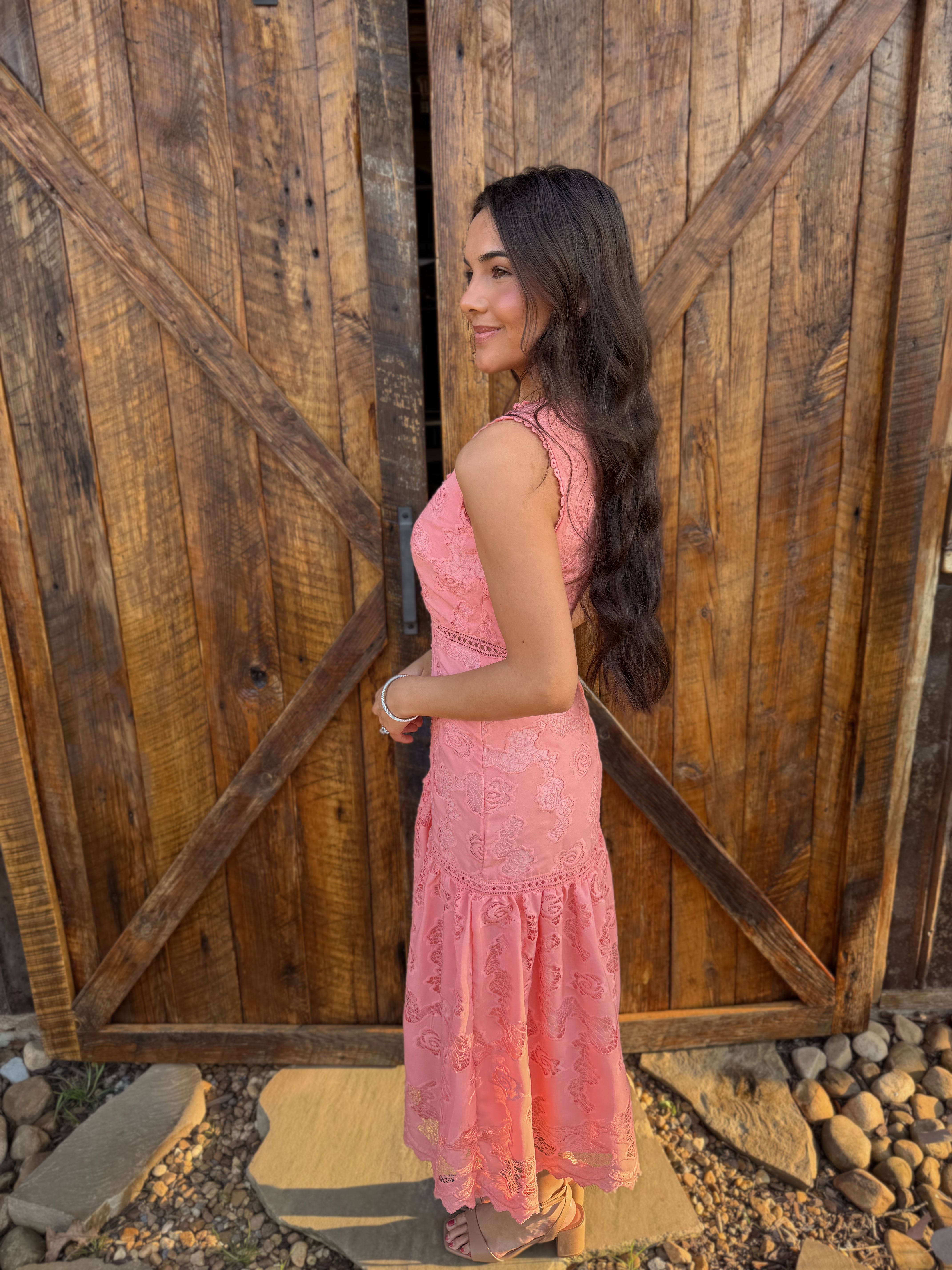 Woman in a pink dress standing in front of a wooden door
