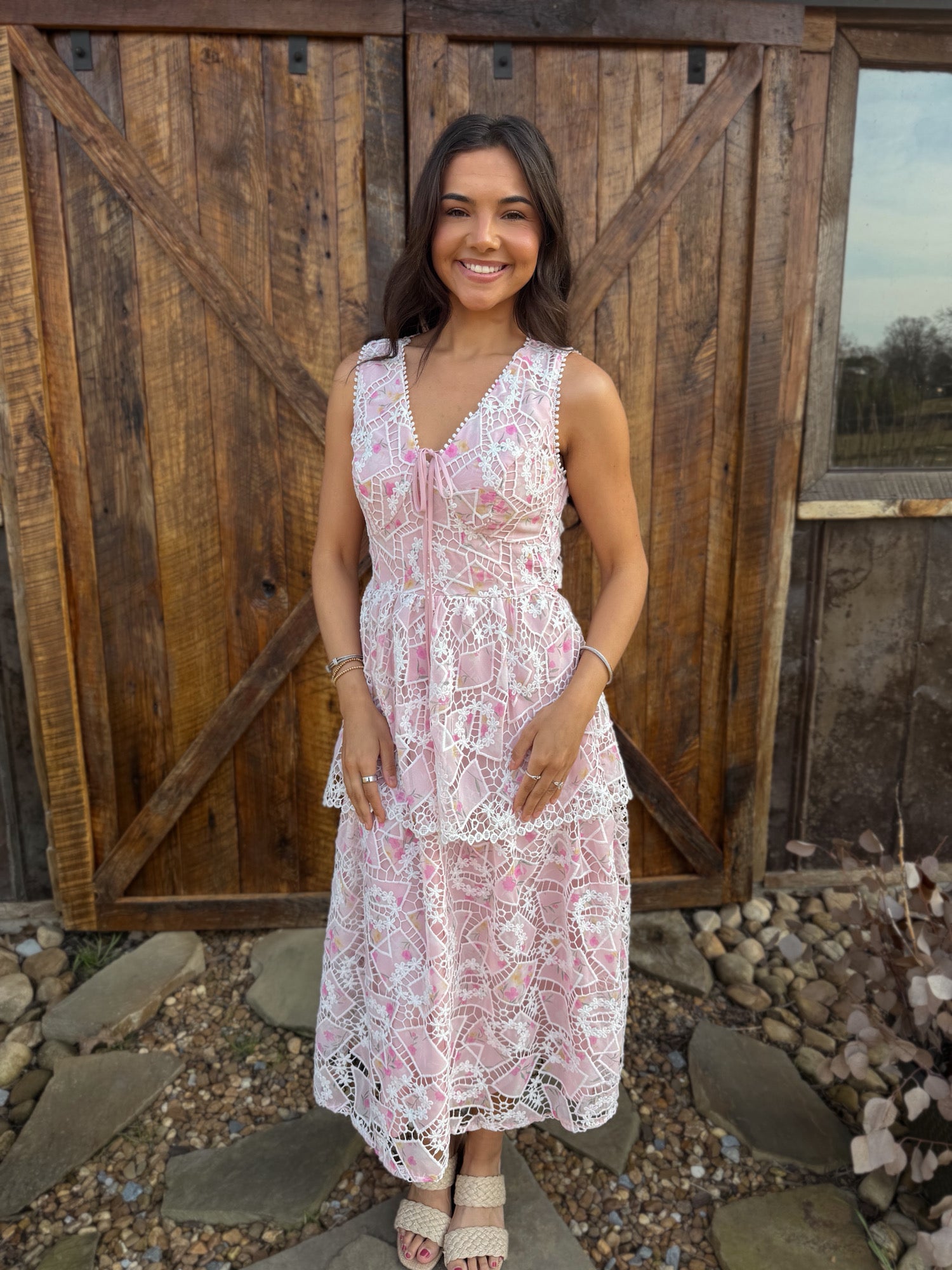 Woman in a white lace dress standing in front of a wooden door.
