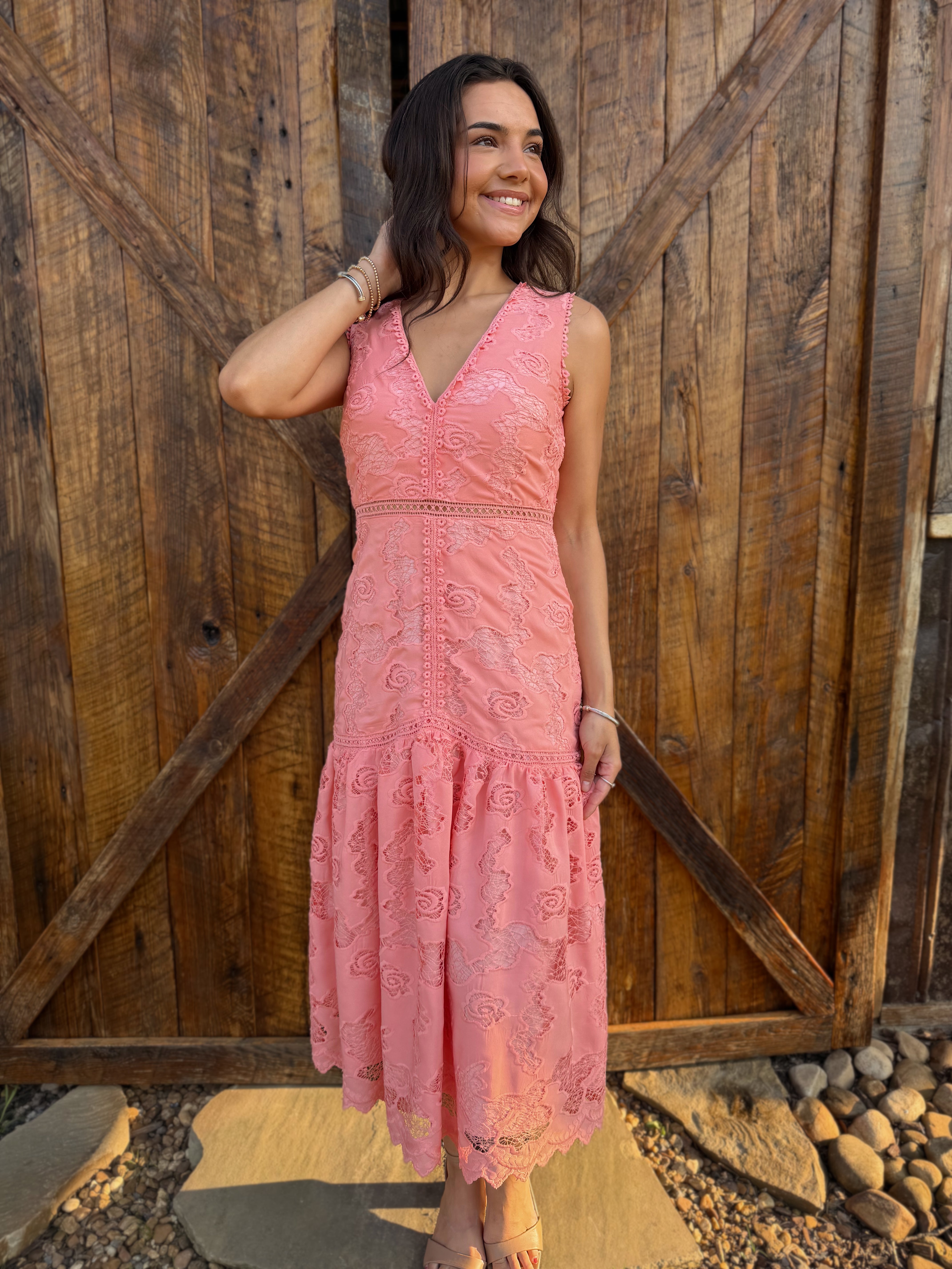 Woman in a pink dress standing in front of a wooden door 